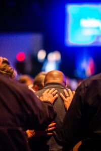 A group of people supporting each other in prayer during a church event, conveying a sense of community and faith.